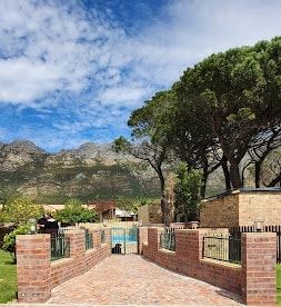 WildWind resort entrance gate with brick pillars, tall trees and Hottentots Holland mountains