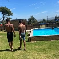 Two guests walking along the WildWind pool lawn with mountain views behind them