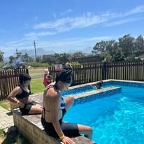 Guests sitting on the edge of the WildWind pool on a sunny day